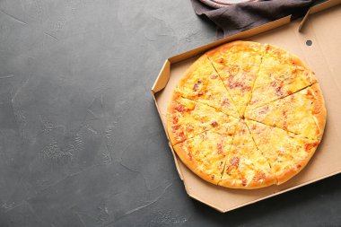 Koyu arkaplanda lezzetli pizzalar olan karton kutu.