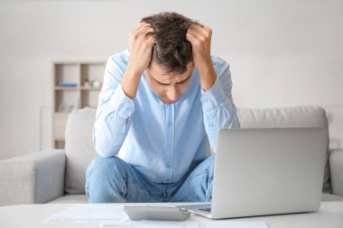 Evde dizüstü bilgisayarı ve hesap makinesi olan stresli bir adam var. İflas kavramı