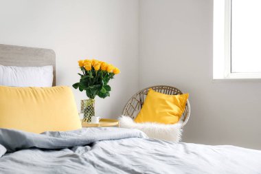 Komodinin üzerinde güzel sarı güller olan vazo.