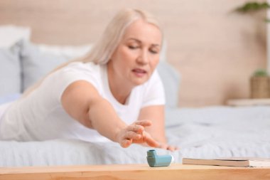 Olgun kadın masadan astım ilacı alıyor.