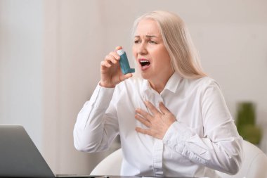 Astımı olan olgun bir kadın ofiste astım krizi geçiriyor.