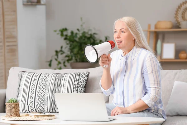 Screaming mature woman with megaphone at home