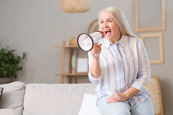 Screaming mature woman with megaphone at home