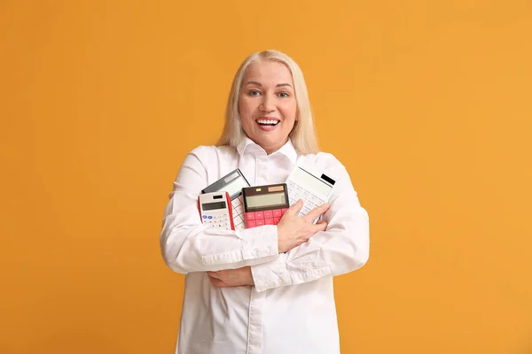 Mature woman with calculators on color background