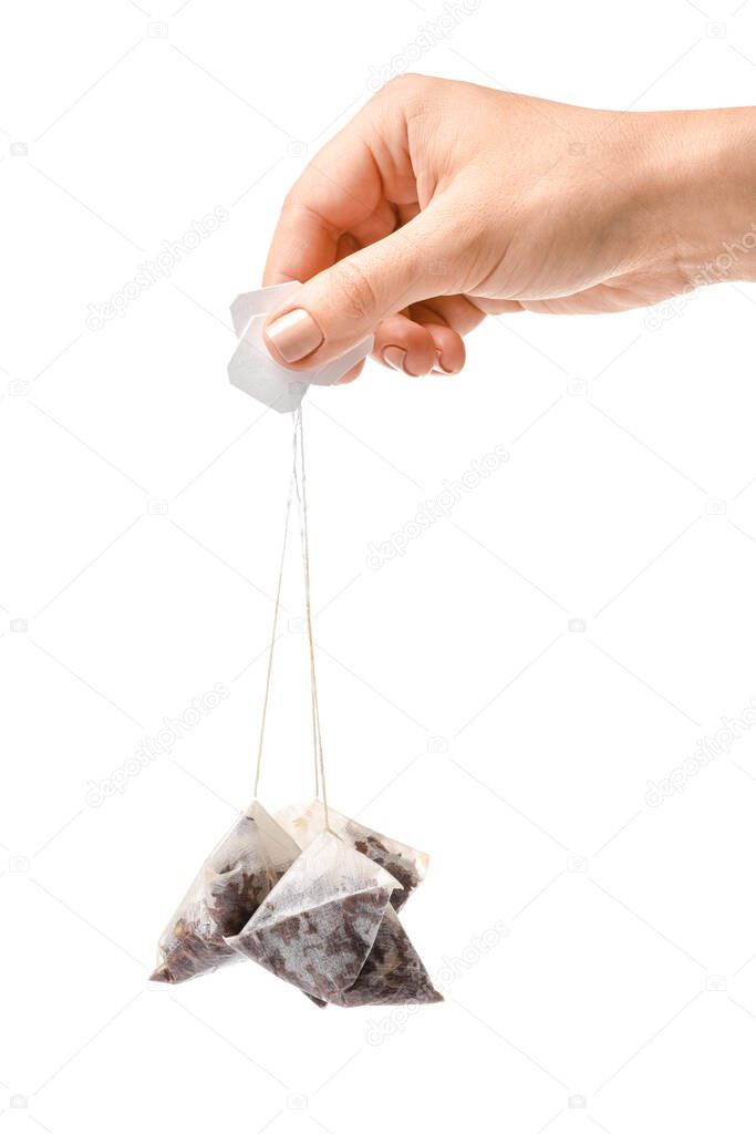 Female hand with used tea bags on white background