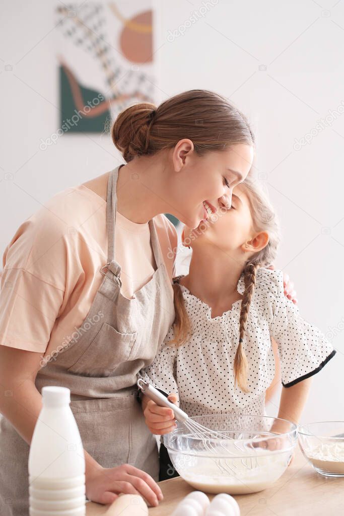 Happy woman and her little daughter cooking in kitchen