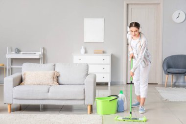 Genç bir kadın odayı paspaslıyor.