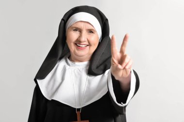 Başrahibe arka planda zafer jesti gösteriyor.