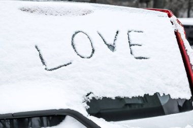 Kar kaplı araba camına yazılmış sözcük aşkı.