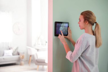 Akıllı ev güvenlik sistemi kontrol paneli kullanan kadın