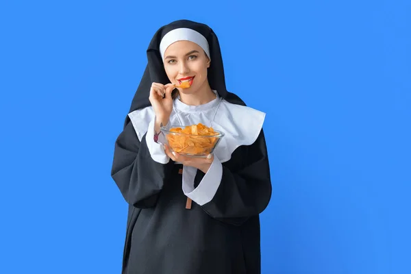 Sexy Nonne Isst Chips Auf Farbigem Hintergrund — Stockfoto