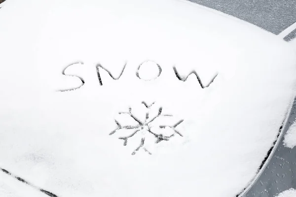 Word SNOW written on car window on winter day
