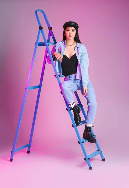 Portrait of stylish Asian woman with ladder on color background