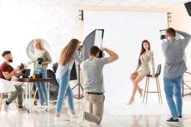 Genç fotoğrafçılar stüdyoda bir kadının fotoğrafını çekiyor.