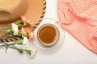 Bir fincan çiçekli kahve ve beyaz arka planda kadın kıyafetleri.