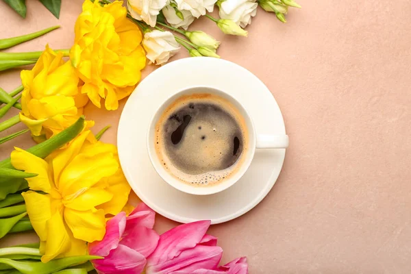 Cup of coffee with spring flowers on color background