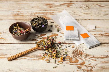 Hafif ahşap arka planda çay poşetleri ve kuru otlar.