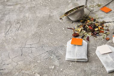 Çay poşetleri ve gri arka planda kuru otlar.