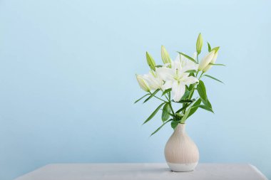 Masanın üzerinde güzel zambak çiçekleri olan vazo renk arkaplanına karşı