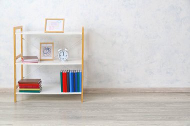 Işık duvarının yanında kitapları ve dekorasyonu olan modern raf ünitesi