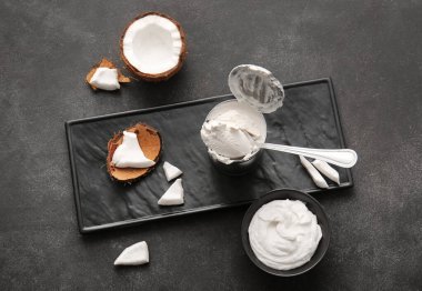 Koyu arkaplanda hindistan cevizi kremalı kase ve metal kutu.