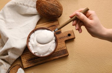 Kaşıklı kadın eli ve arka planda hindistan cevizi kremalı kase.