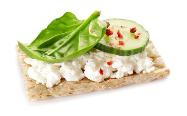 Süzme peynirli çıtır ekmek, beyaz arka planda salatalık ve fesleğen.