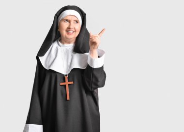 Başrahibe arka plandaki bir şeyi işaret ediyor.