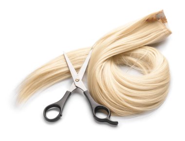 Beyaz arka planda kuaför makası olan saç teli.