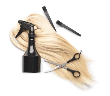 Beyaz arka planda kuaför aletleri olan saç teli.