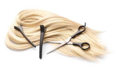 Beyaz arka planda kuaför aletleri olan saç teli.