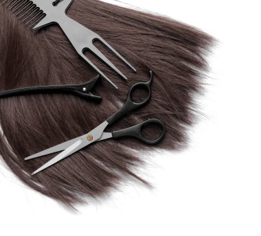 Beyaz arka planda kuaför aletleri olan saç teli.