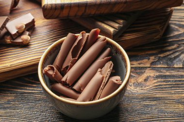 Tahta masanın üzerinde lezzetli çikolata bukleleri olan kase, yakın plan.