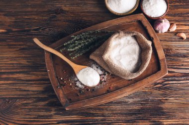 Tahta arka planda kaşık ve tuz torbasıyla kompozisyon