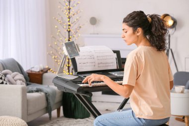 Evde müzik dersleri veren genç bir kadın.