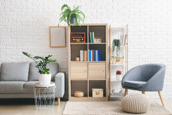 Interior of modern room with shelf units, sofa and armchair