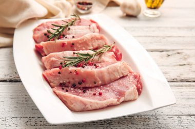 Taze çiğ et tabağı ve hafif ahşap arka planda baharatlar.