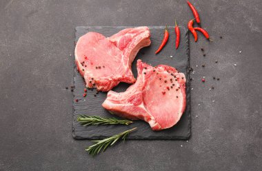 Koyu arkaplanda taze çiğ et ve baharatlar.