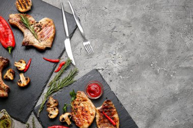 Gri arka planda lezzetli biftekli ve baharatlı tahtalar