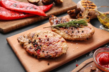 Lezzetli biftekleri ve koyu arkaplanda baharatları olan bir pano.