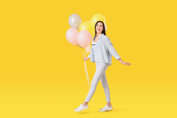 Beautiful young woman with balloons on color background