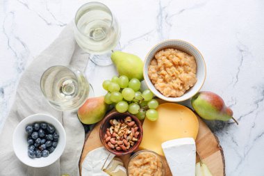 Farklı peynirli armut reçeli, beyaz arka planda fındık ve şarap.