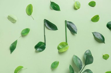 Renk arkaplanındaki yeşil yapraklardan yapılmış notalar