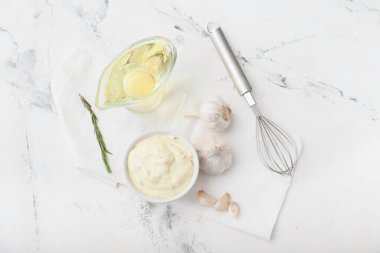 Sarımsak soslu kase ve beyaz arka planda malzemeler.