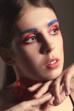 Esmer arka planda olağandışı makyajlı güzel bir kadın. Yakın plan.