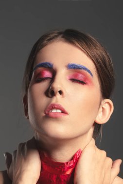 Esmer arka planda olağandışı makyajı olan güzel bir kadın.