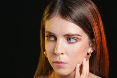 Esmer arka planda olağandışı makyajı olan güzel bir kadın.