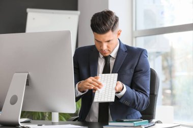 Genç işadamı ofiste bilgisayarını temizliyor