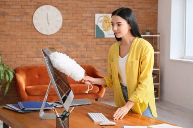 Evde bilgisayar temizleyen genç bir kadın.