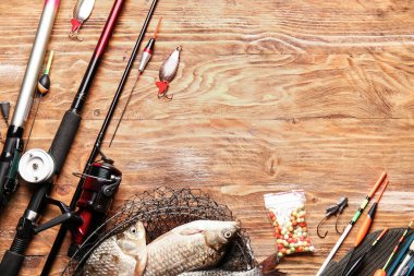 Ahşap arka planda farklı balıkçılık ekipmanları ve balıklar